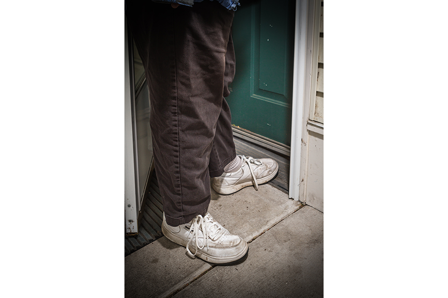 A women's feet as she stands on the metal plating that provide a zero-step threshold into her home.